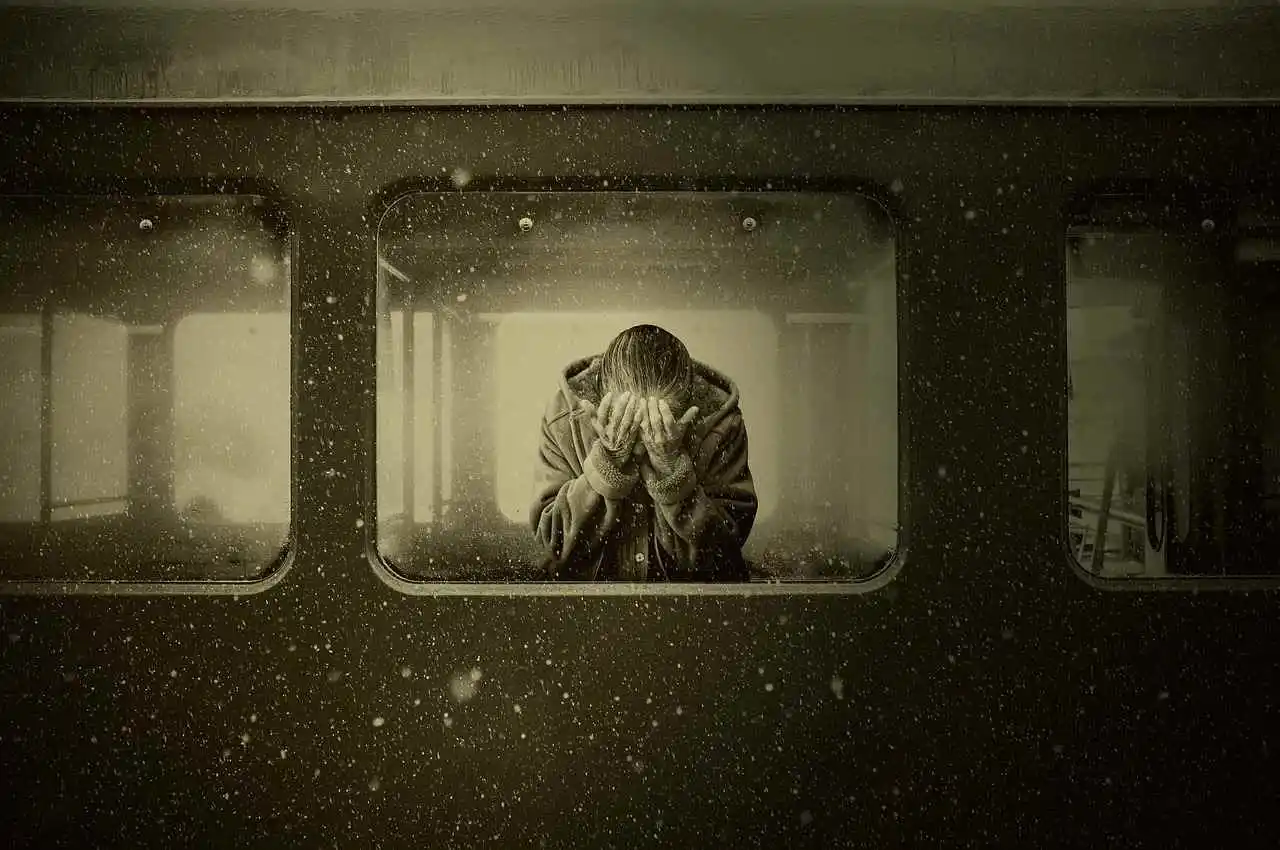 Femme en détresse émotionnelle se couvrant le visage avec ses mains à l'intérieur d'un train