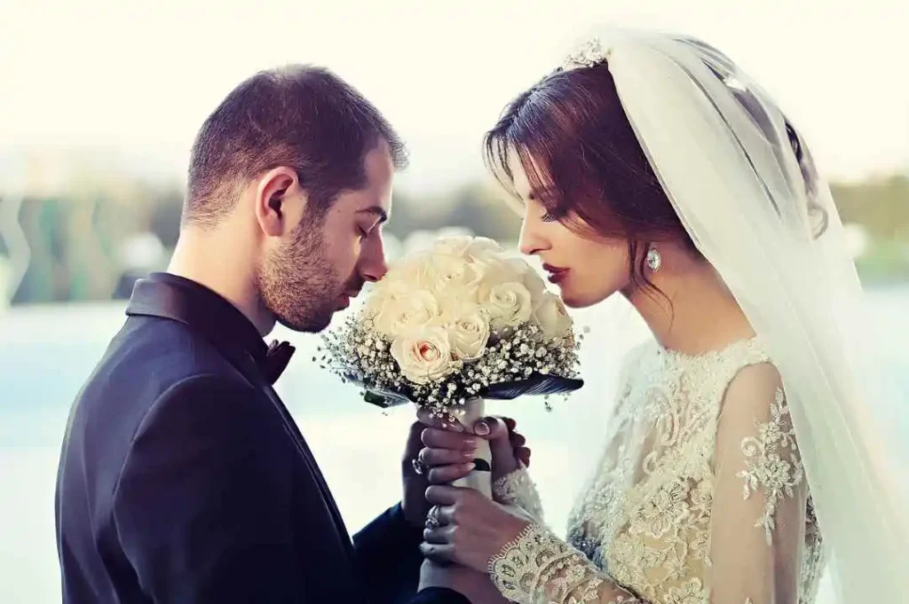 Une mariée et un marié tenant un charmant bouquet de fleurs, symbolisant la beauté et l'unité dans leur nouveau voyage d'amour.