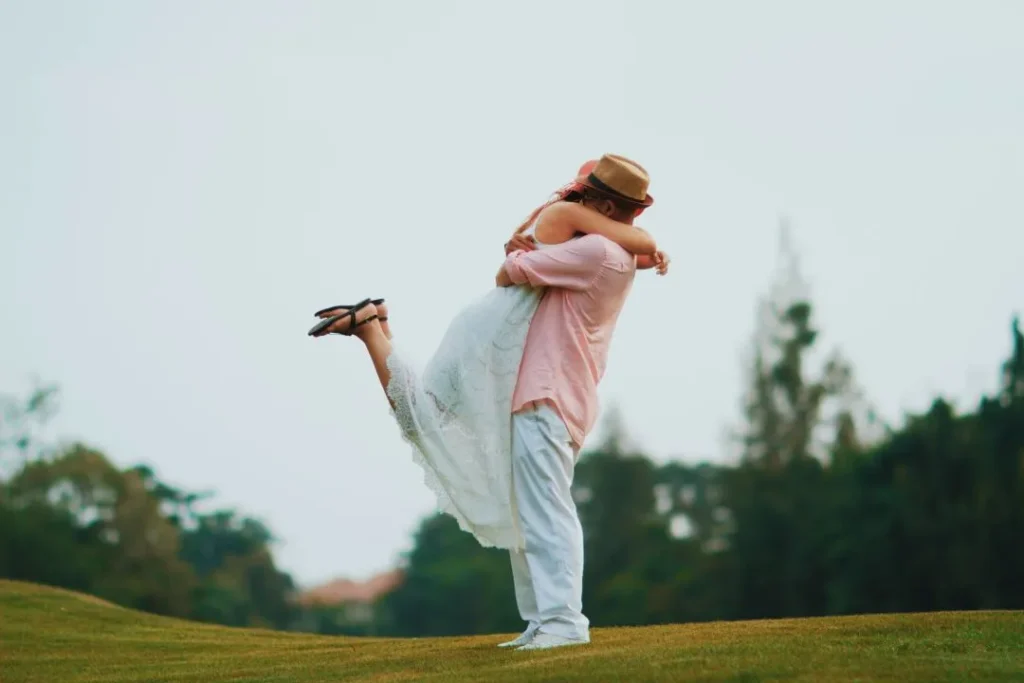 Moment romantique - Un garçon porte sa femme dans ses bras dans un parc verdoyant.