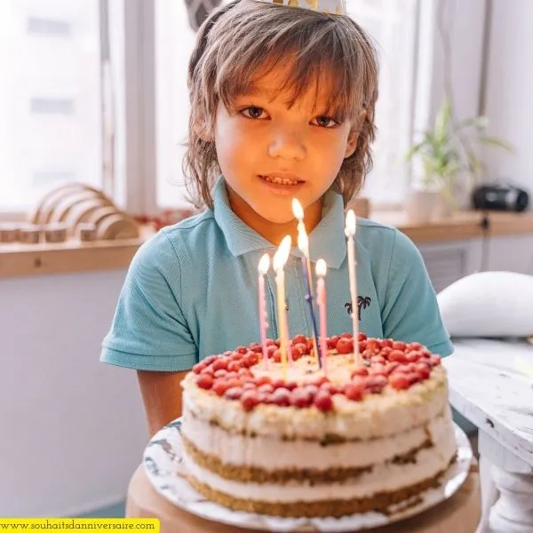 Un jeune garçon de 8 ans au visage ovale et aux longs cheveux tenant un gâteau illuminé de bougies, délicieusement tentant.
