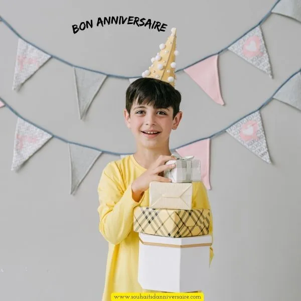 Un petit garçon de 5 ans ouvre ses cadeaux d'anniversaire avec un large sourire, vêtu d'un t-shirt jaune, et célèbre sa journée spéciale avec joie.